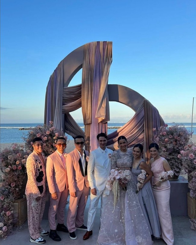 Sang suami, Michael Wahr yang berasal dari Australia, mengenakan setelan jas putih dengan korsase pink dan sepatu pantofel coklat. Foto: Instagram