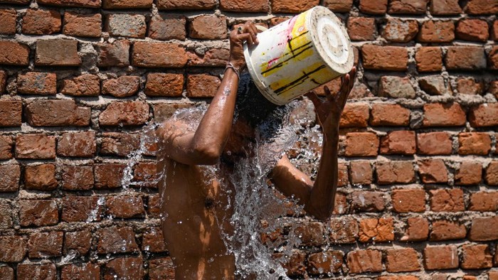 Panasnya cuaca di India membuat sejumlah warga melakukan cara untuk mendinginkan tubuhnya. Seperti anak-anak di New Delhi ini.