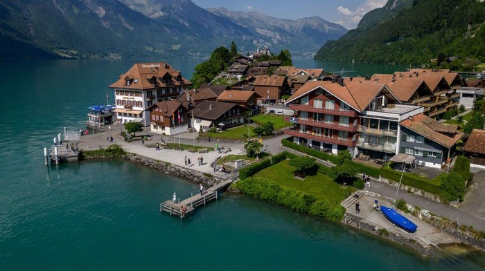 Tourists take a selfie on the famous pier seen in a popular South Korean series on Netflix, in the village of Iseltwald at the shore of Lake Brienz, in the Swiss Alps, on June 2, 2023. Ever since a hugely popular South Korean series on Netflix featured a romantic scene in this very spot, the picturesque lakeside village of Iseltwald, with a population of around 400 people, has found itself overrun by tourists. They are fans of 
