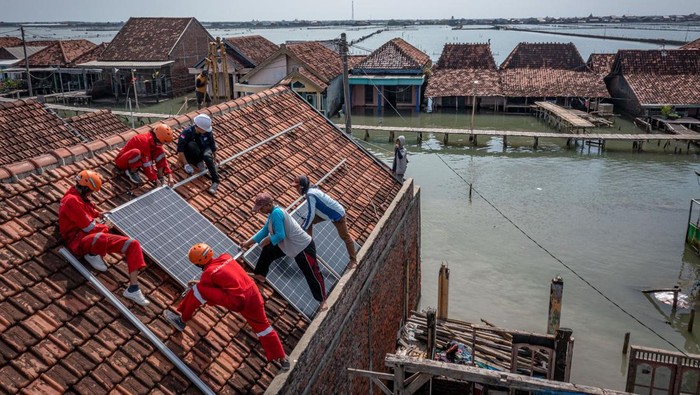 Anti Token, Pompa Air di Dukuh Ini Beroperasi Pakai Listrik Atap Warga bersama aktivis lingkungan Greenpeace Indonesia memasang instalasi panel surya untuk pompa air di Dukuh Timbulsloko yang terkepung air laut akibat terdampak penurunan tanah disertai kenaikan air laut di Kecamatan Sayung, Kabupaten Demak, Jawa Tengah, Senin (12/6/2023). Bantuan pompa air berkekuatan 3.500 liter per jam bertenaga panel surya berkapasitas 3.200 watt peak melalui program Penggalangan Dana Masyarakat Alirkan Harapan Untuk Timbulsloko itu untuk mengaliri kebutuhan air bersih 138 kepala keluarga dan empat rumah ibadah yang dapat menghemat biaya konsumsi listrik kampung tersebut hingga sekitar Rp2.500.000 per bulan, serta sebagai kampanye penggunaan energi terbarukan yang hemat dan ramah lingkungan sekaligus mencegah krisis iklim. ANTARA FOTO/Aji Styawan/rwa.