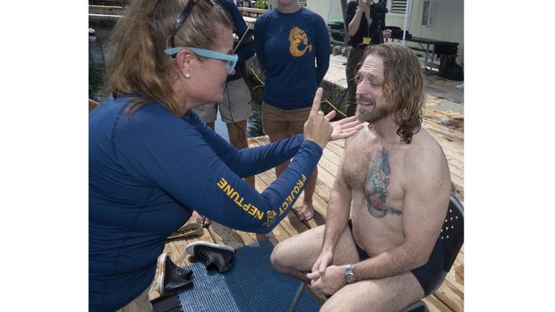 In this photo provided by the Florida Keys News Bureau, diving explorer and medical researcher Dr. Joseph Dituri, left, basks in the sun Friday, June 9, 2023, after completing a 100-day underwater mission in the Jules' Undersea Lodge marine habitat at the bottom of a lagoon in Key Largo, Fla. Dituri broke the previous 73-day record for underwater human habitation at ambient pressure, undertook medical and marine science research and interacted online with more than 5,500 students during his Project Neptune 100 mission organized by the Marine Resources Development Foundation. (Andy Newman/Florida Keys News Bureau via AP)