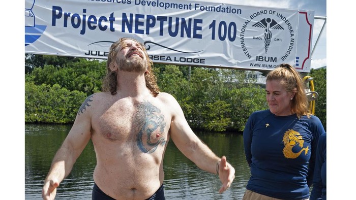 In this photo provided by the Florida Keys News Bureau, diving explorer and medical researcher Dr. Joseph Dituri, left, basks in the sun Friday, June 9, 2023, after completing a 100-day underwater mission in the Jules' Undersea Lodge marine habitat at the bottom of a lagoon in Key Largo, Fla. Dituri broke the previous 73-day record for underwater human habitation at ambient pressure, undertook medical and marine science research and interacted online with more than 5,500 students during his Project Neptune 100 mission organized by the Marine Resources Development Foundation. (Andy Newman/Florida Keys News Bureau via AP)