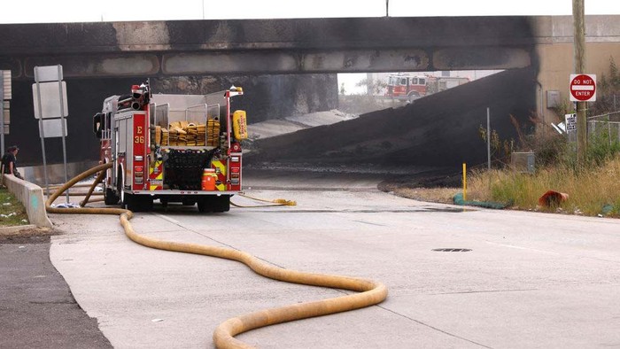 Gegara Truk Terbakar, Jalan Layang di AS Ambruk A retroexcavator removes parts of a collapsed portion of Interstate 95, caused by a large vehicle fire, in Philadelphia, Pennsylvania, on June 11, 2023. A fire caused part of a busy US highway overpass to collapse in Philadelphia early Sunday, authorities said, as reports attributed the accident to an oil tanker that burst into flames under the bridge. The collapse took out four traffic lanes along an elevated section of the heavily traveled motorway, though no injuries were immediately reported. (Photo by KENA BETANCUR / AFP) (Photo by KENA BETANCUR/AFP via Getty Images)