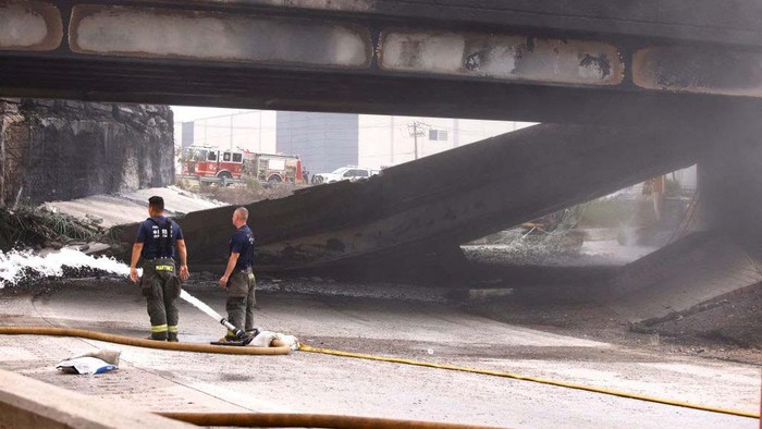 Gegara Truk Terbakar, Jalan Layang di AS Ambruk A retroexcavator removes parts of a collapsed portion of Interstate 95, caused by a large vehicle fire, in Philadelphia, Pennsylvania, on June 11, 2023. A fire caused part of a busy US highway overpass to collapse in Philadelphia early Sunday, authorities said, as reports attributed the accident to an oil tanker that burst into flames under the bridge. The collapse took out four traffic lanes along an elevated section of the heavily traveled motorway, though no injuries were immediately reported. (Photo by KENA BETANCUR / AFP) (Photo by KENA BETANCUR/AFP via Getty Images)