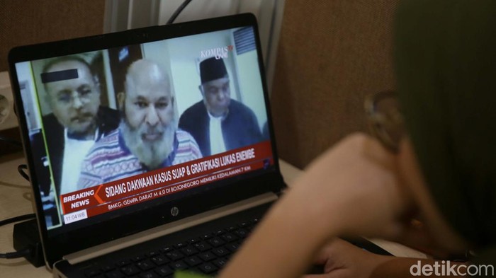 Lukas Enembe menjalani sidang perdana dalam kasus suap dan gratifikasi. Lukas akan menjalani sidang secara daring (online) dari Gedung KPK.