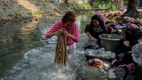 Warga memilih mencuci baju di sungai yang tercemar dalam upaya menghemat air bersih.  