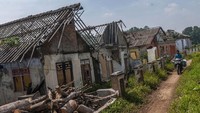 Pengendara sepeda motor melintas di samping rumah yang mulai dirobohkan di Kampung Susukan, Lebak, Banten, Senin (12/6/2023).  