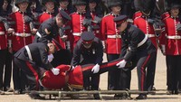 Seorang tentara dibawa dengan tandu setelah pingsan selama Tinjauan Kolonel.  