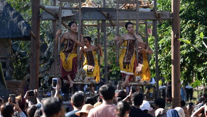 Remaja putri menaiki ayunan Jantra di Desa Tenganan Pegringsingan, Karangasem, Bali, Minggu (11/6/2023). Tradisi Ayunan Jantra itu menyimbolkan kondisi kehidupan manusia yang terus berputar dan menjadi atraksi wisata yang menarik bagi wisatawan domestik maupun mancanegara yang berkunjung. 
ANTARA FOTO/Fikri Yusuf/nz