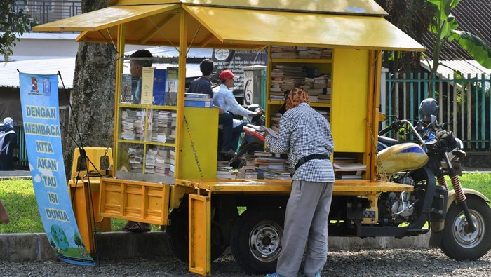 Warga membaca buku di perpustakaan keliling, Taman Manunggal, Kota Bogor, Jawa Barat, Selasa (13/6/2023). Perpustakaan keliling dengan memanfaatkan bekas sepeda motor sampah tersebut sebagai gerakan untuk meningkatkan literasi membaca di kalangan anak-anak dan masyarakat. ANTARA FOTO/Arif Firmansyah/foc.