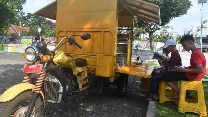 Warga membaca buku di perpustakaan keliling, Taman Manunggal, Kota Bogor, Jawa Barat, Selasa (13/6/2023). Perpustakaan keliling dengan memanfaatkan bekas sepeda motor sampah tersebut sebagai gerakan untuk meningkatkan literasi membaca di kalangan anak-anak dan masyarakat. ANTARA FOTO/Arif Firmansyah/foc.