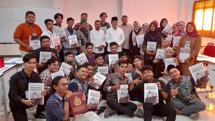 Romo Syafii membagi-bagikan buku Paradoks Indonesia.