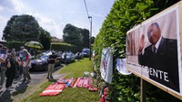Foto Silvio Berlusconi sedang melambaikan tangan terpajang di depan rumah di Arcore, Italia, Senin (12/6/2023) waktu setempat.  