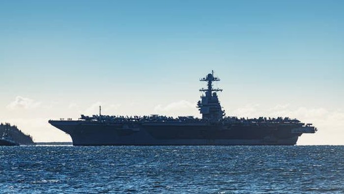 Navy aircraft carrier enters a harbour after offshore training exercises.