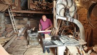 Pembuat perahu Elias Barbour memulai harinya dengan menyalakan generator pribadinya agar dapat menjalankan mesinnya untuk memotong kayu, Kamis (8/6/2023).  