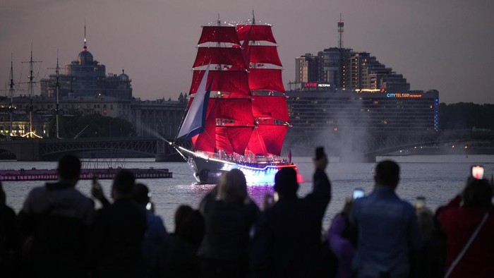 A brig with scarlet sails floats on the Neva River through the Troitsky drawbridge during a rehearsal for the Scarlet Sails festivities marking school graduation in St. Petersburg, Russia, early Tuesday, June 13, 2023. (AP Photo/Dmitri Lovetsky)