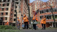 Sejumlah petugas kebersihan bekerja membersihkan halaman salah satu pusat perbelanjaan yang rusak akibat serangan rudal Rusia, di Odesa, Ukraina, Rabu (14/6/2023).