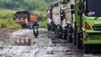 Pengendara motor melintas di antara truk-truk yang mengangkut pasir.  