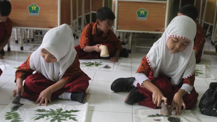 Sejumlah siswa membuat motif daun dengan teknik cetak ecoprint pada tas jinjing berbahan kain kanvas di SDN Tanjungrejo 5, Malang, Jawa Timur, Kamis (15/6/2023). Kegiatan tersebut diikuti 46 siswa untuk memberikan edukasi tentang pemanfaatan bahan alami ramah lingkungan dalam pembuatan karya kreatif. ANTARA FOTO/Ari Bowo Sucipto/nym.