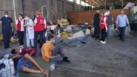 Sementara di Pelabuhan Kalamata, sekitar 70 penyintas yang kelelahan tampak tertidur di kantong-kantong tidur berselimut yang disediakan oleh tim penyelamat di sebuah gudang, sementara paramedis mendirikan tenda bagi siapa pun yang membutuhkan pertolongan pertama. AP/Uncredited  