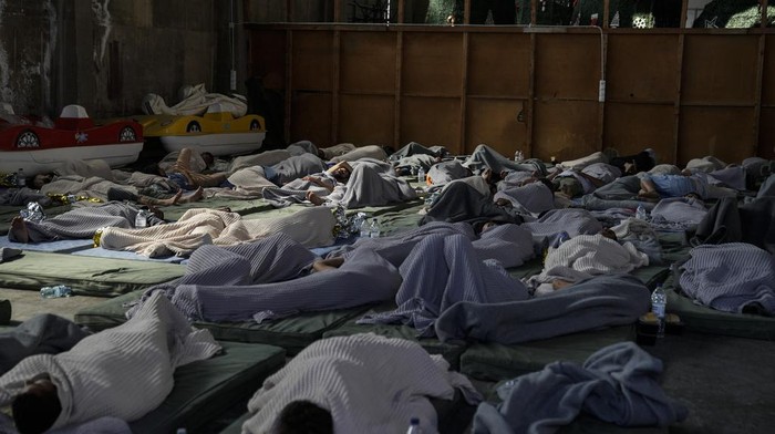 Survivors of a shipwreck sleep at a warehouse at the port in Kalamata town, about 240 kilometers (150 miles) southwest of Athens, Wednesday, June 14, 2023. A fishing boat carrying migrants capsized and sank off the coast of Greece on Wednesday, authorities said, leaving at least 78 people dead and many dozens feared missing in one of the worst disasters of its kind this year. (AP Photos/Thanassis Stavrakis)