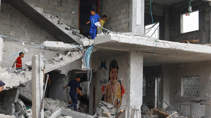 Palestinian children walk near a graffiti, as artists draw graffiti on houses destroyed by Israel in recent Israeli-Gaza fighting, in Deir Al-Balah, central Gaza Strip June 8, 2023. REUTERS/Ibraheem Abu Mustafa