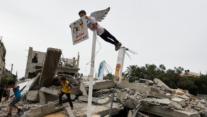 Palestinian children walk near a graffiti, as artists draw graffiti on houses destroyed by Israel in recent Israeli-Gaza fighting, in Deir Al-Balah, central Gaza Strip June 8, 2023. REUTERS/Ibraheem Abu Mustafa