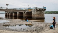 Penduduk setempat membersihkan pantai kota, yang penuh dengan sampah setelah permukaan air di sungai Dnipro turun tajam. REUTERS/Alina Smutko  