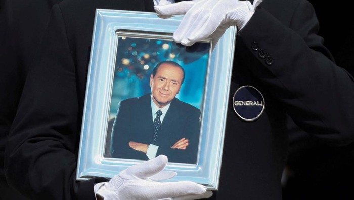 Potret Pemakaman Mantan PM Italia Silvio Berlusconi A pallbearer holds a portrait of former Italian Prime Minister Silvio Berlusconi while walking in front of the coffin during his state funeral at the Duomo Cathedral, in Milan, Italy June 14, 2023. REUTERS/Yara Nardi