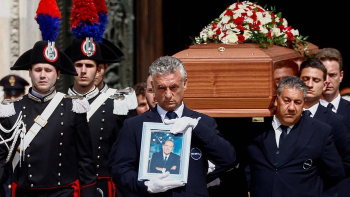A pallbearer holds a portrait of former Italian Prime Minister Silvio Berlusconi while walking in front of the coffin during his state funeral at the Duomo Cathedral, in Milan, Italy June 14, 2023. REUTERS/Yara Nardi