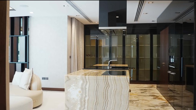 Ada dua ruang tamu di rumah crazy rich Dubai ini. Ruangan dengan sofa putih ini salah satunya. Ruangan tampak homey dengan tambahan dekor selimut dan bantal kursi serta pemandangan area kolam renang dan pepohonan. Foto: Dok. YouTube Luxe List