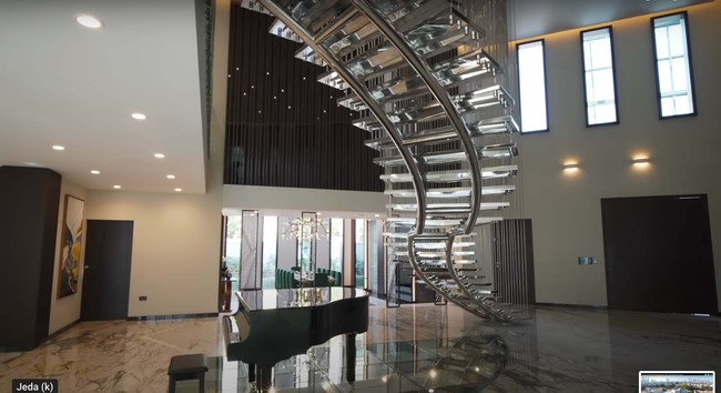 Setelah membuka pintu depan rumah, aura kemewahan langsung terlihat dengan hadirnya grand piano yang diletakkan di atas lantai kaca transparan. Ada juga tangga silver yang bentuknya bak karya seni. Foto: Dok. YouTube Luxe List