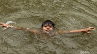 Di tengah hujan dan arus yang cukup deras, anak-anak ini menunjukkan kebolehannya dalam berenang.  