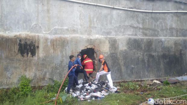 Petugas pemadam kemudian menjebol dinding samping gudang agar bisa menyemprotkan air ke bagian belakang gudang. Meski demikian petugas masih kesulitan memadamkan api.