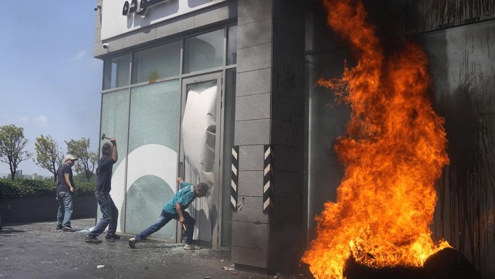 Lebanon Membara! Bank-bank Dirusak Nasabah yang Minta Dana Dikembalikan A protester throws a bottle of oil at the windows of Bank Audi during a protest demanding the release of depositors' trapped savings, in Beirut, Lebanon, Thursday, June 15, 2023. Since Lebanon fell into a financial crisis in 2019, the banks have imposed informal capital controls, restricting depositors from accessing their funds, while the country's currency has collapsed and inflation has spiraled. (AP Photo/Hussein Malla)