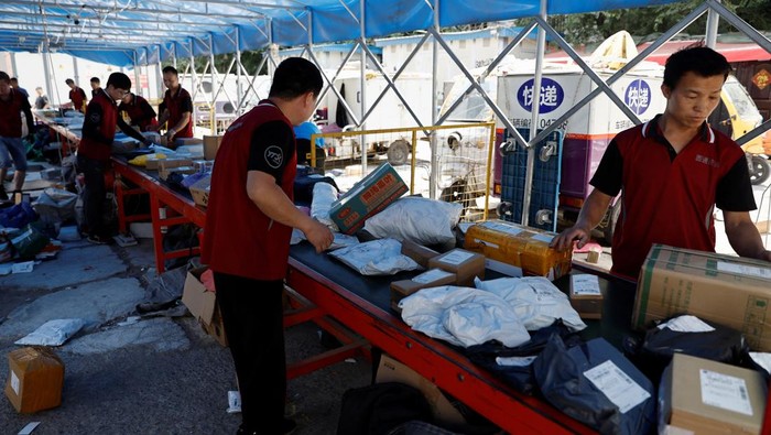 Delivery workers sort packages on a conveyor belt, ahead of the 