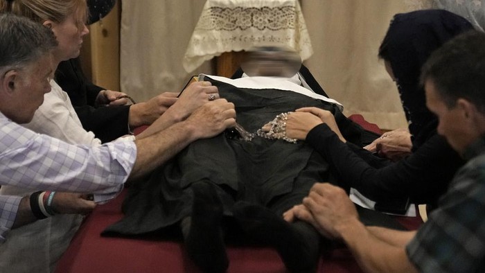 People pray over the body of Sister Wilhelmina Lancaster at the Benedictines of Mary, Queen of Apostles abbey Sunday, May 28, 2023, near Gower, Mo. Hundreds of people visited the small town in Missouri this week to see the nun's body that has barely decomposed since 2019 — some are saying it's a sign of holiness in Catholicism, while others are saying the lack of decomposition may not be as rare as people think.  (AP Photo/Charlie Riedel)
