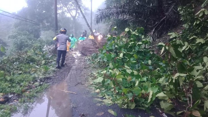 Petugas kepolisian sedang membersihkan material longsor di jalan penghubung Minahasa menuju Minahasa Utara, Sulawesi Utara.