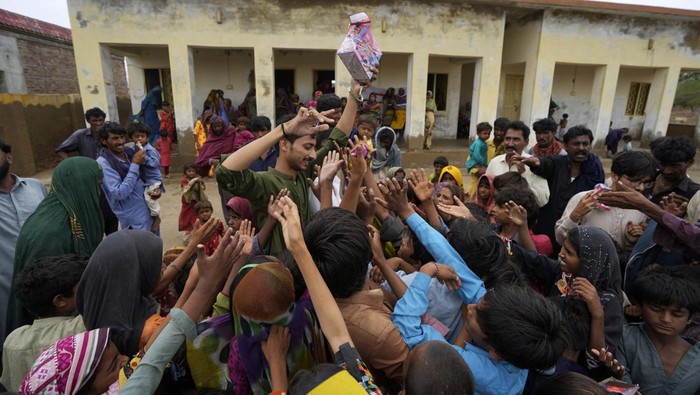 Potret Warga Pakistan Korban Topan Biparjoy Antre Makanan A volunteer distributes food items among children at a camp set up in a school building for internally displaced people from coastal areas, as Cyclone Biparjoy was approaching, in Badin, Pakistan's southern district in the Sindh province, Thursday, June 15, 2023. A vast swath of western India and neighboring southern Pakistan that suffered deadly floods last year are bracing for a new deluge as fast-approaching Cyclone Biparjoy whirls toward landfall Thursday. (AP Photo/Fareed Khan)