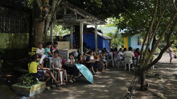 An evacuee looks out of their room as students hold class along the hallways, because the school was converted into a temporary evacuation center, at Malilipot town, Albay province, northeastern Philippines, Thursday, June 15, 2023. Thousands of residents have left the mostly poor farming communities within a 6-kilometer (3.7-mile) radius of Mayon's crater in forced evacuations since volcanic activity spiked last week. (AP Photo/Aaron Favila)