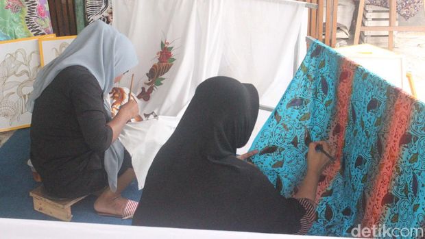 Foto: Dua pengerajin sedang merapikan ukiran batik diatas kain.(Alamudin)