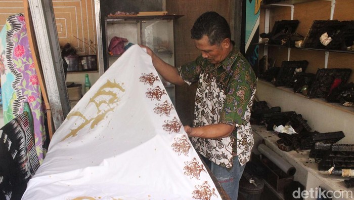Foto: Suratno sedang merapikan kain untuk dicap dengan alat yang telah disediakan.(Alamudin)
