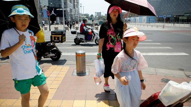 Orang-orang yang memakai topi pelindung matahari berjalan di bawah sinar matahari pada hari yang panas di tengah peringatan oranye untuk gelombang panas, di Beijing, China 16 Juni 2023. (REUTERS/Florence Lo)