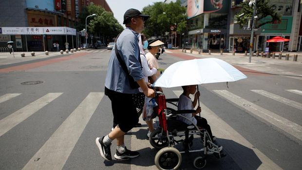 Pejalan kaki menyeberang jalan di hari yang panas di tengah peringatan oranye untuk gelombang panas, di Beijing, China 16 Juni 2023. (REUTERS/Florence Lo)