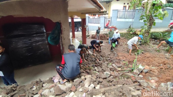Sejumlah warga bergotong royong membantu membersihkan material tebing longsor yang menerjang rumah warga.