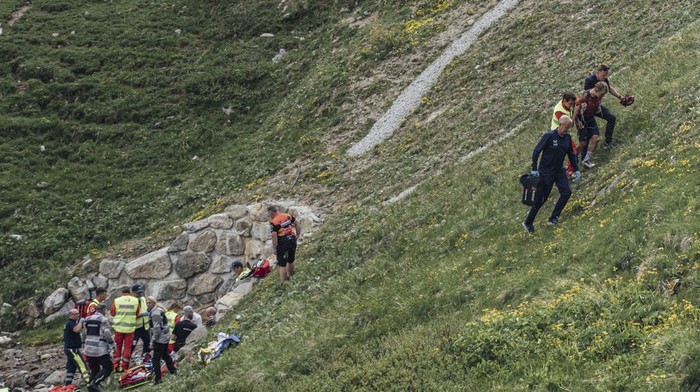 Switzerlands Gino Mader, left, receives medical attention after crashing as Magnus Sheffield of the United States, right, is helped away, during the fifth stage of the Tour de Suisse, Tour of Switzerland cycling race, in Punt, Thursday, June 15, 2023. Swiss cyclist Gino Mader has died one day after crashing and falling down a ravine during a descent at the Tour de Suisse. The Bahrain-Victorious team announced the news. The 26-year-old Mader crashed on a fast downhill road approaching the end of the mountainous fifth stage into La Punt. (SWpix/Zac Williams/Keystone via AP)