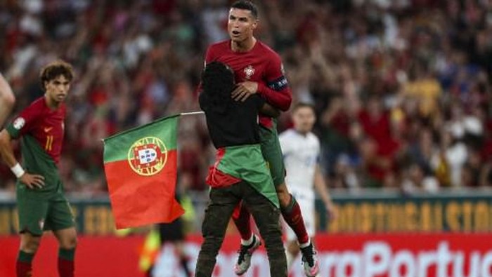 A supporter invades the pitch and grabs Portugals forward Cristiano Ronaldo during the UEFA Euro 2024 group J qualification football match between Portugal and Bosnia-Herzegovina at the Luz stadium in Lisbon on June 17, 2023. (Photo by CARLOS COSTA / AFP)