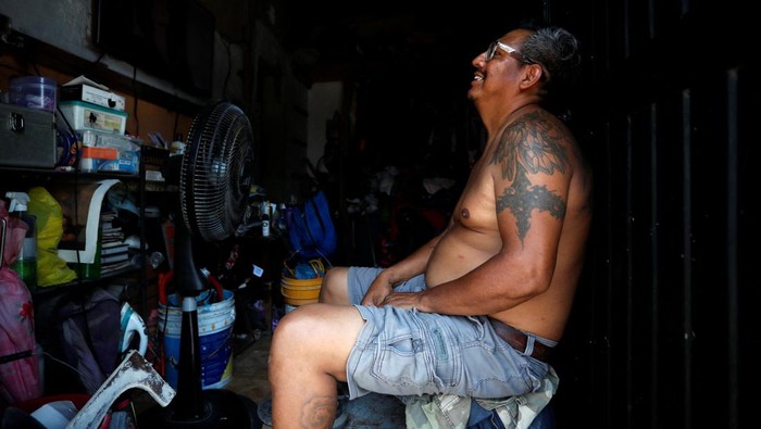 A man watches television while cooling himself with an electric ventilator as temperatures rise during an unusual heat wave, in Monterrey, Mexico June 15, 2023. REUTERS/Daniel Becerril