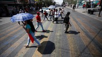 Warga memakai payung saat menyeberangi jalan menyusul terjadinya peningkatan suhu udara yang tidak seperti biasanya di Monterrey, Meksiko, Kamis (15/6/2023). 