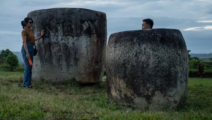 Negeri seribu megalit di Poso Sejumlah pengunjung mengamati Kalamba atau bejana batu raksasa di kawasan Situs Megalit Pokokea, Desa Baliura, Lore Tengah, Poso, Sulawesi Tengah, Sabtu (17/6/2023). Sedikitnya terdapat 950 titik persebaran benda peninggalan zaman batu sejenis bejana dan patung berusia lebih dari 3000 tahun di kawasan itu dan untuk menarik kunjungan wisata, Pemerintah Provinsi Sulawesi Tengah akan mencanangkan tahun ini sebagai tahun kunjungan wisata dengan tagline Negeri Seribu Megalit. ANTARA FOTO/Basri Marzuki